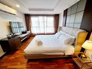 A hotel room with a bed, a desk, a TV, and a window with curtains. - Luxurious 2-bedroom Condo With Pool View Near BTS Ekkamai Station (Bangkok)