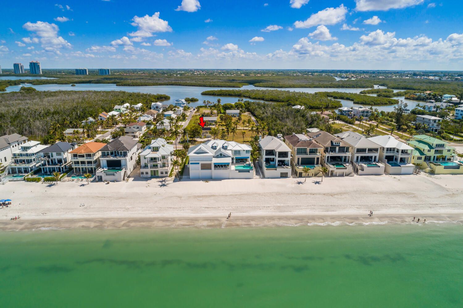 A coastal resort with beachfront villas, a marina, and a view of the surrounding water and greenery.