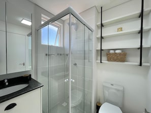 Ein modernes Badezimmer mit einer Duschkabine aus Glas, einer weißen Toilette und einer schwarzen Ablagefläche.