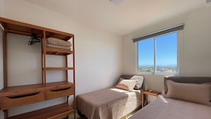 Quarto com beliche, estante de madeira e janela com vista para a cidade.