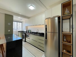 Cozinha moderna com eletrodomésticos de aço inoxidável, forno embutido e janela que traz luz natural.