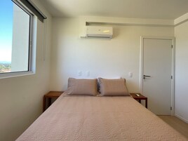 Quarto com cama, janela, ar-condicionado e porta.