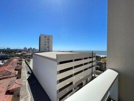 Um edifício com telhado plano e vários andares, próximo a uma área costeira sob um céu limpo.