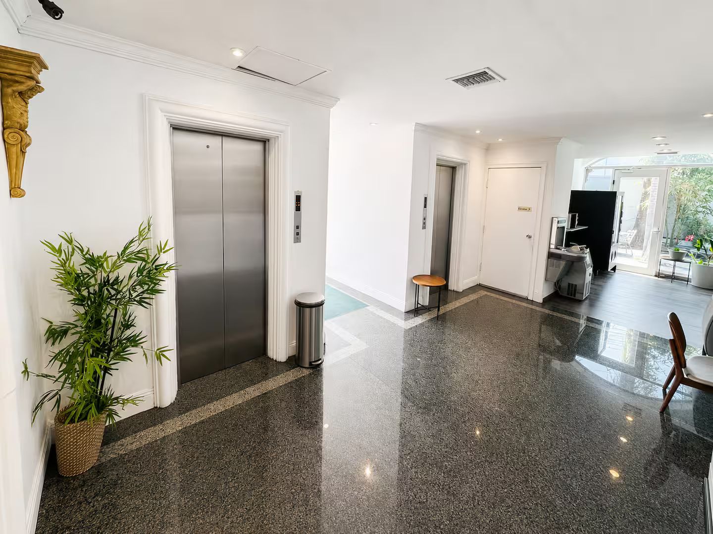 Eine moderne Hotelhalle mit einem glatten Boden, einer Rezeption und einer großen Pflanze in einem Topf.