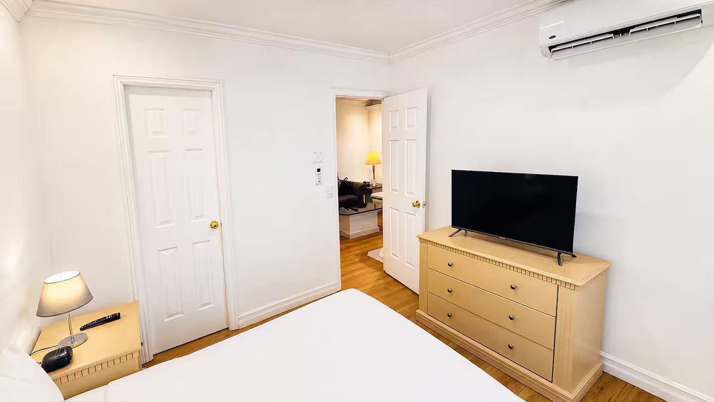 Ein Hotelzimmer mit einem Bett, einem Schminktisch, einem Fernseher und einer Klimaanlage.
