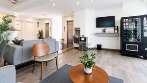 Ein modernes Wohnzimmer mit einem grauen Sofa, einem Holztisch und einem an der Wand befestigten Fernseher.
