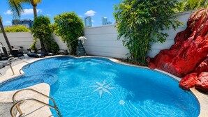 Ein Pool mit einem Seestern-Design, umgeben von Palmen und roten Felsen.