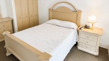 Ein Schlafzimmer mit einem Bett, einem Nachttisch, einer Lampe, einem Deckenventilator und einem Kleiderschrank.