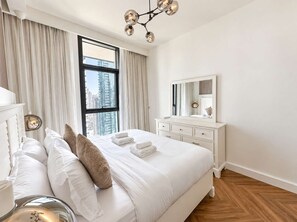 Een hotelkamer met een groot bed, een kaptafel, een spiegel en uitzicht op de stad door een raam.