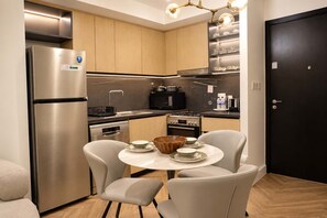 A compact kitchen with modern appliances, a dining table with chairs, and a black door. - Luxury 1BR Downtown Views Walk to Burj Khalifa (Dubai)