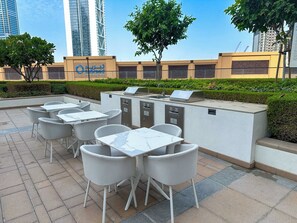 An outdoor seating area with tables and chairs, a water fountain, and a sign for a sustainable golf course. - Luxury 1BR Downtown Views Walk to Burj Khalifa (Dubai)