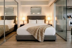 Ein modernes Hotelzimmer mit einem großen Bett, Nachttischlampen, einem Spiegel und einer Küchenzeile.