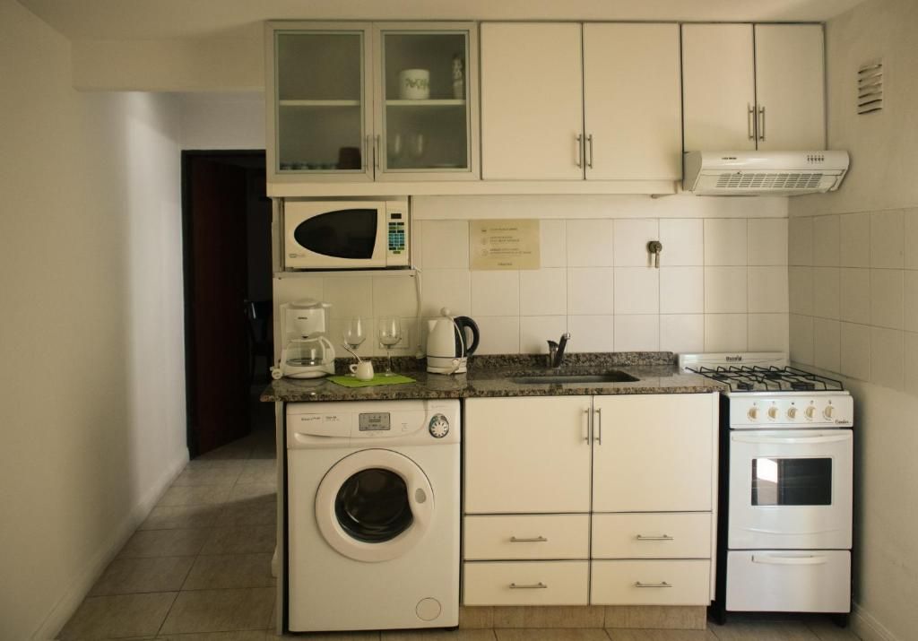 A compact kitchen with a washing machine, microwave, stove, and cabinets.