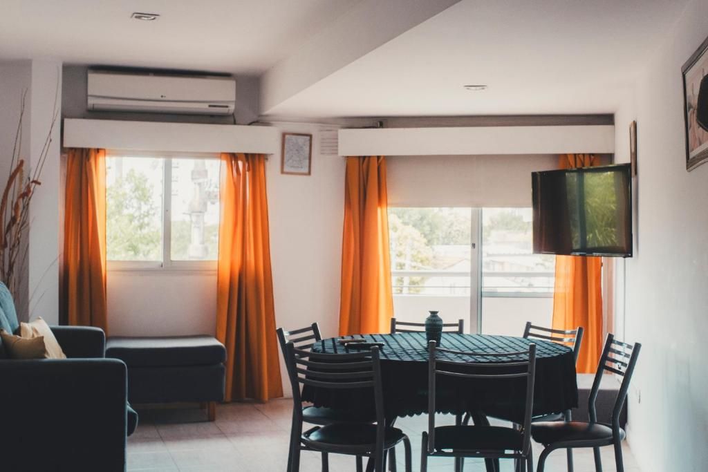 Un área de comedor con una mesa redonda y sillas, un sofá y un televisor en la pared.