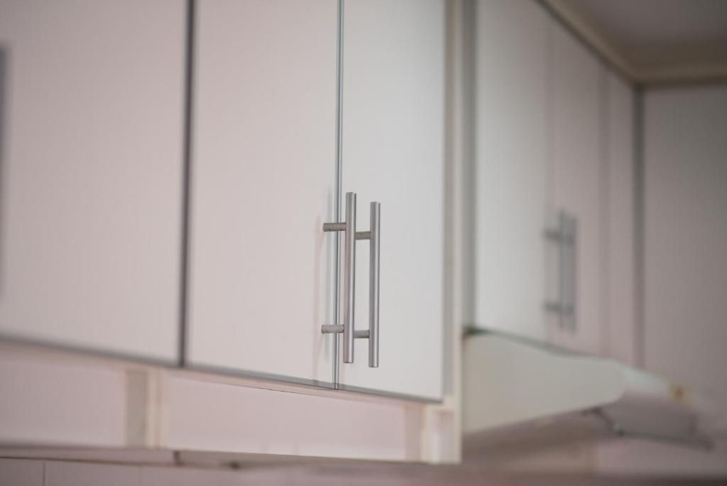 A modern kitchen with white cabinets and stainless steel handles.