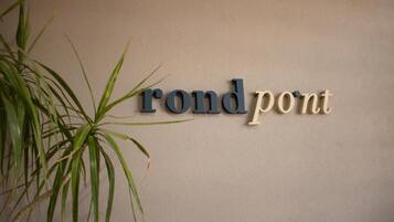 En vägg med texten ”rond pont” skriven med en stiliserad typsnitt, och en växt till vänster.