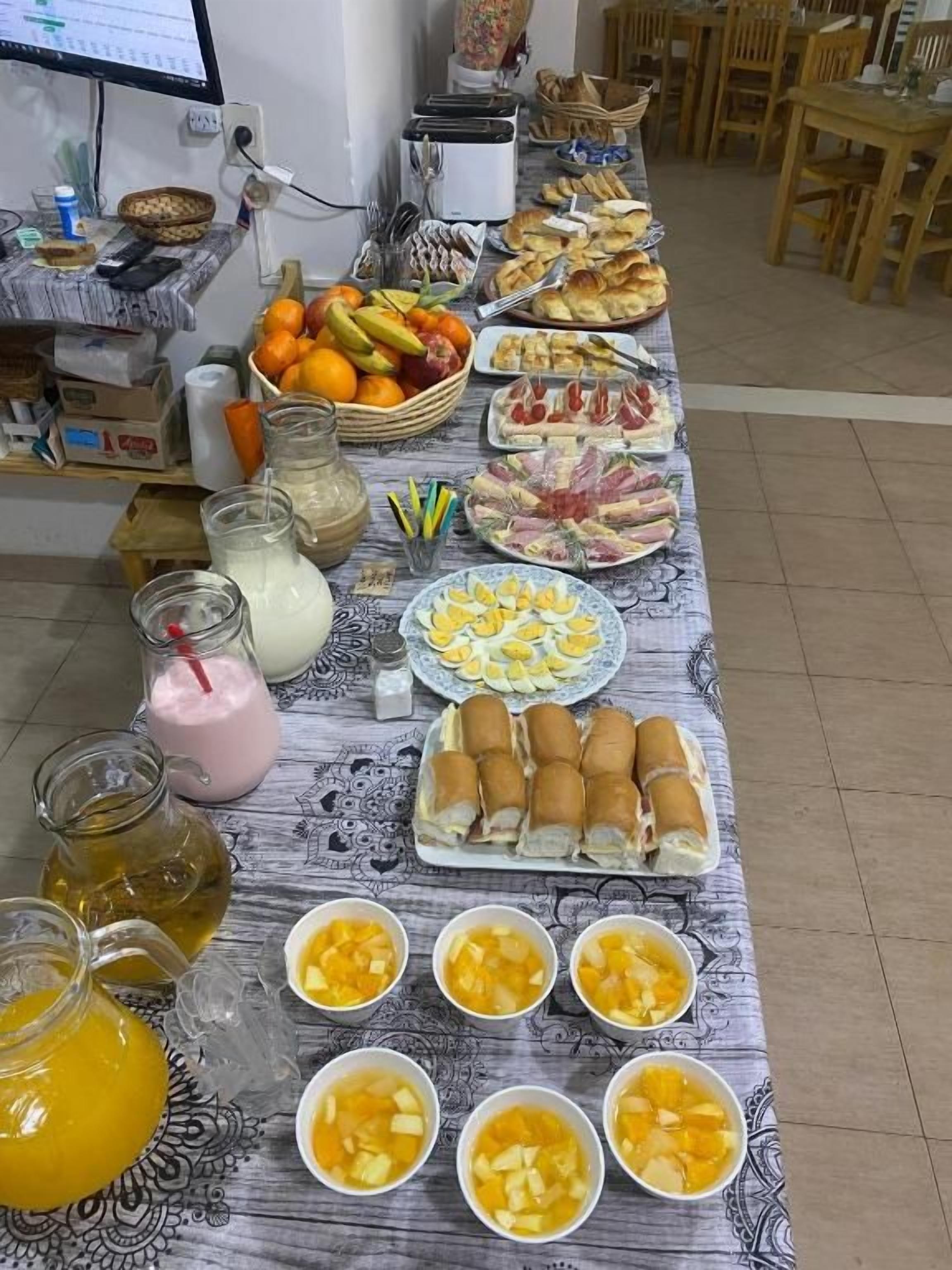 Una mesa dispuesta con diferentes alimentos, entre ellos frutas, sándwiches y bebidas.
