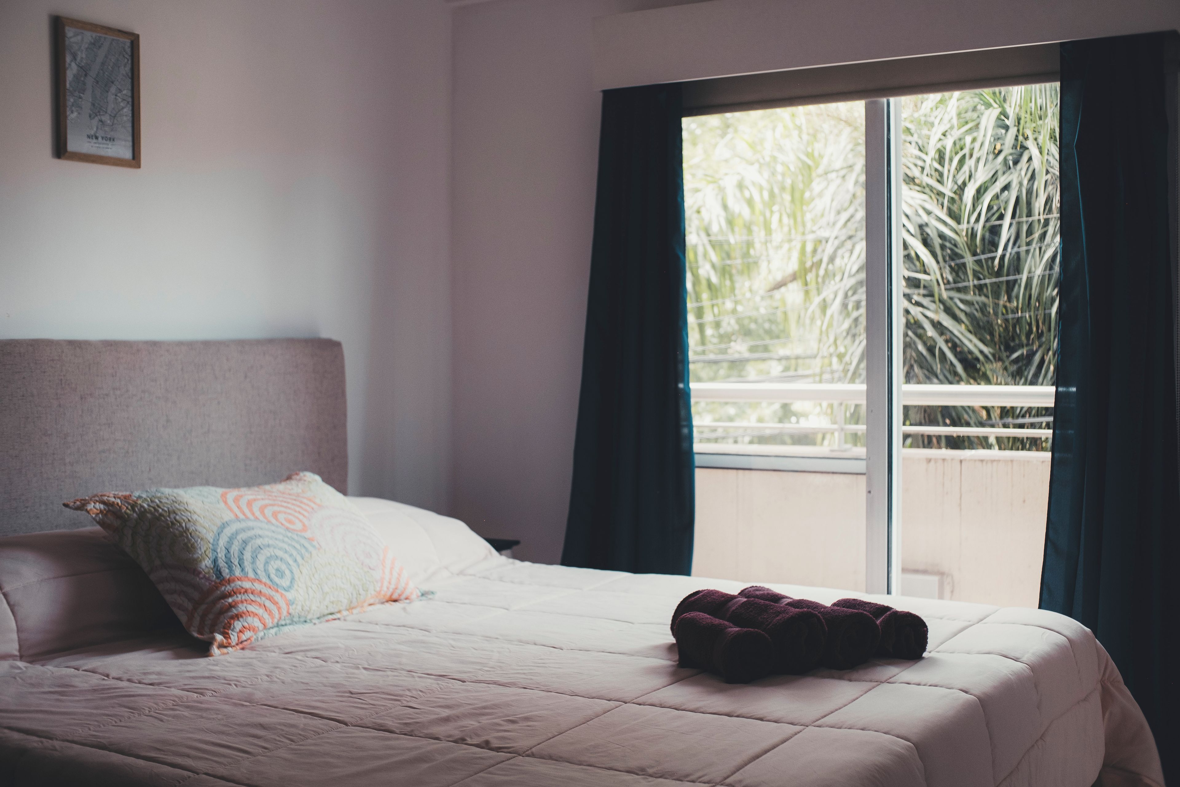 A bedroom with a bed, pillows, a window, and a view of greenery outside.