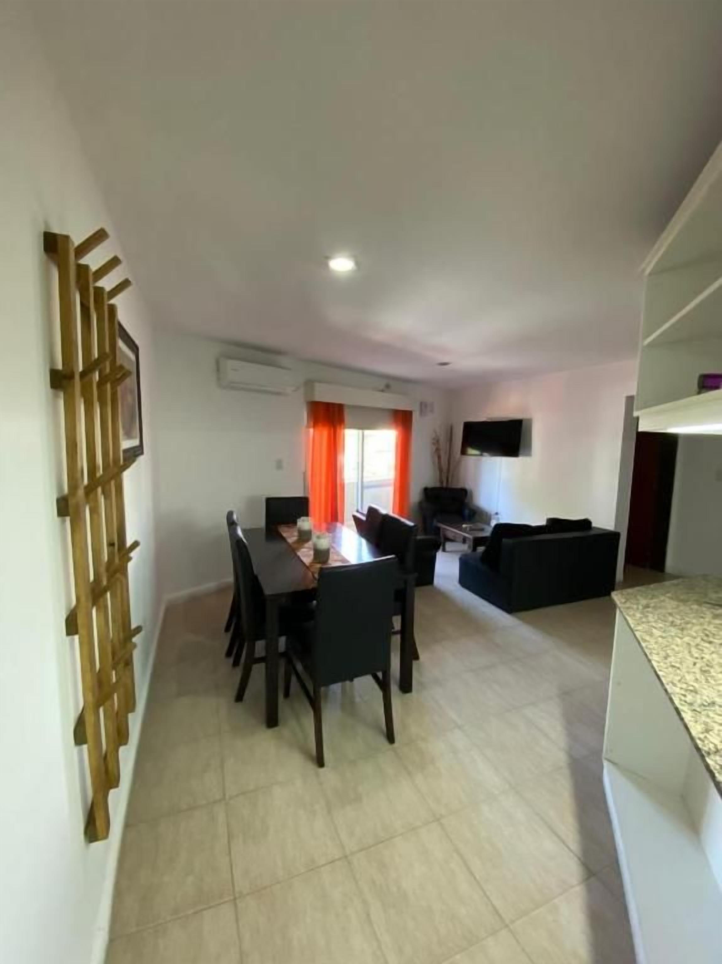 Un área de comedor con una mesa, sillas, un sofá y un televisor.