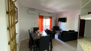 Un área de comedor con una mesa, sillas, un sofá y un televisor.