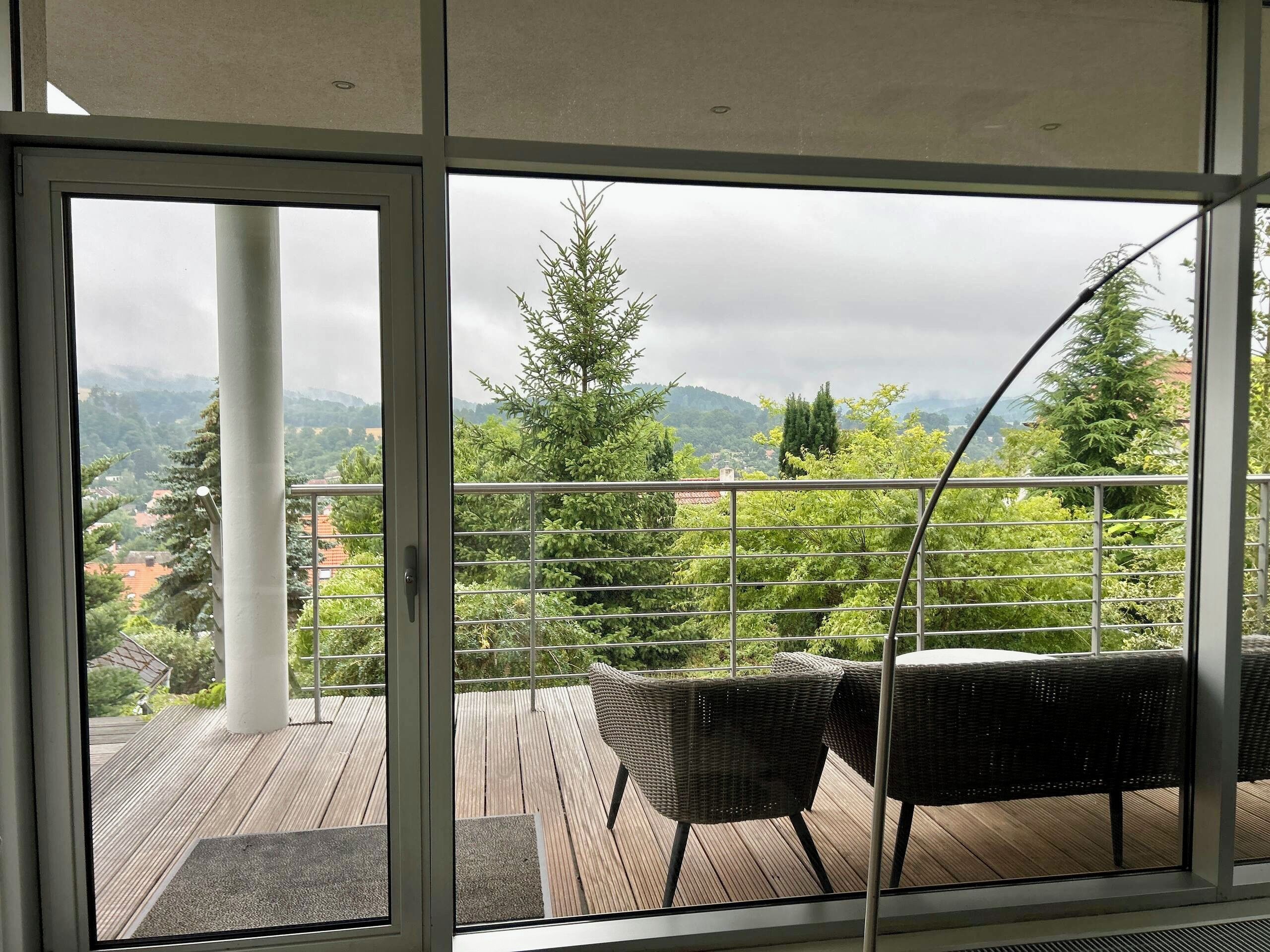Un balcon donnant sur un paysage montagneux, avec une balustrade et des meubles en osier.