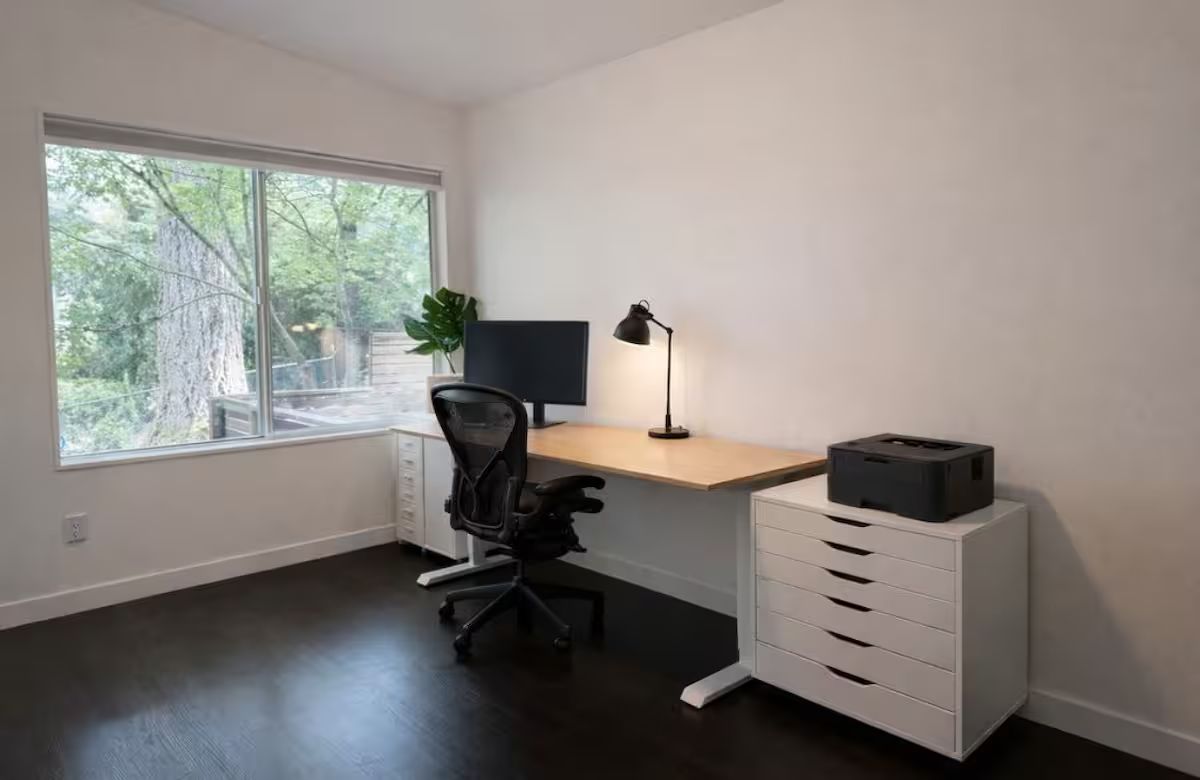 A modern office space with a desk, chair, lamp, and filing cabinet.