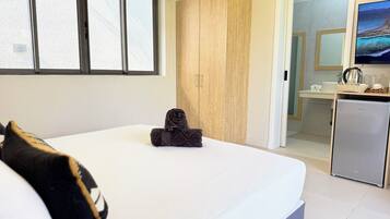 Un dormitorio con cama, armario, kitchenette y baño.