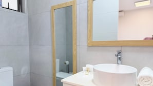 Un baño con lavamanos blanco, un espejo y un inodoro.