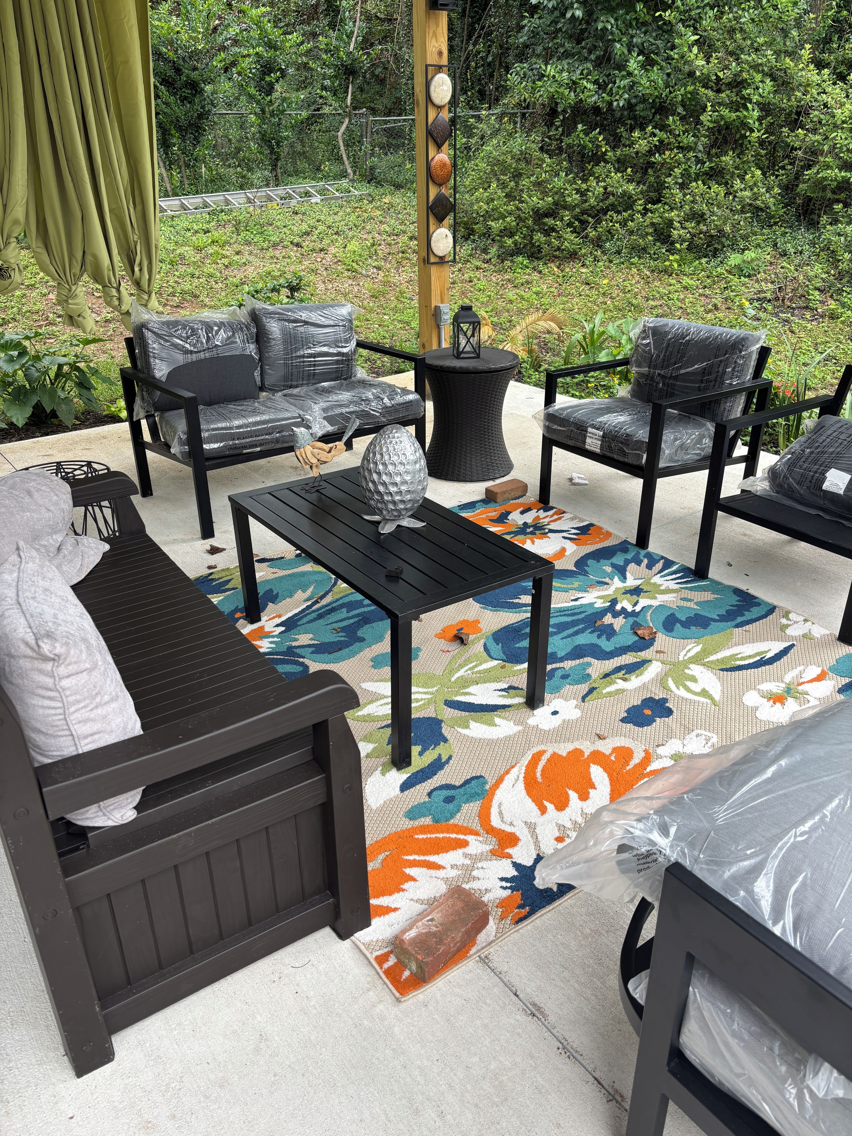 Un espace patio aménagé avec du mobilier d’extérieur, un mur décoratif et un tapis à motifs.