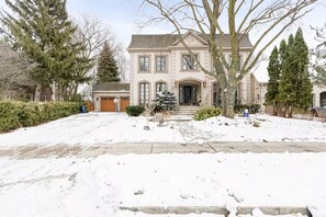 Een twee verdiepingen tellend huis met een oprit en een sneeuwbedekte tuin.