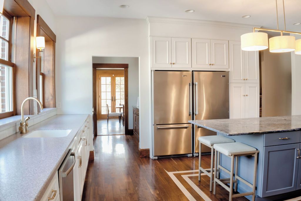 Una cocina moderna con electrodomésticos de acero inoxidable, encimera de mármol y piso de madera.