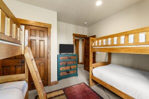 A room with bunk beds, a dresser with animal designs, and a television. - Mountain Village Gem|Hot Tub+Views+Ski-In/Out (Mountain Village)