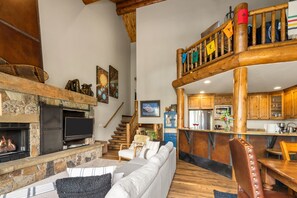 Een ruime woonkamer met een open haard, een bank en een eettafel.