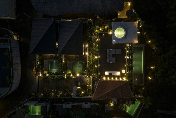 An aerial view of a residential property with multiple rooms, a circular skylight, and outdoor lighting.