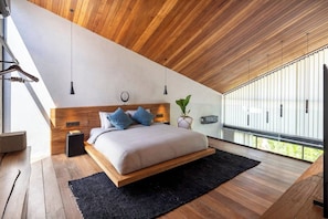 A modern bedroom with a wooden ceiling, a bed with a headboard, a black rug, and a potted plant. - KINOH Loft II Private Pool & Tropical Design (South Kuta)