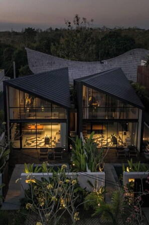 A modern house with two main sections, each with a sloped roof and large glass windows.