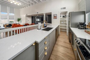 A modern kitchen with a central island, built-in appliances, and a dining area with red chairs. - 2 Lux twin townhomes/King bds/Pool tables/Groups (Phoenix)