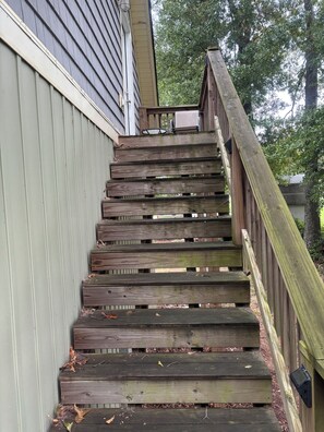 A wooden staircase with a handrail leading to a house.