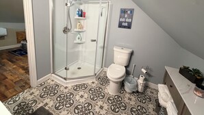 Un bagno con doccia vetrata, un water e un lavabo con piano in marmo.