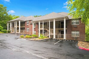 A two-story building with a covered entrance and a parking lot. - Central Branson Suite • 2 Queen Beds • Sleeps 4 (Branson)