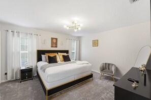 Ein Schlafzimmer mit einem Bett, Nachttischen, einem Sessel, einem Schreibtisch und einer Wandleuchte.