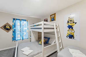 Quarto com beliche, cortina e arte nas paredes com tema Minion.