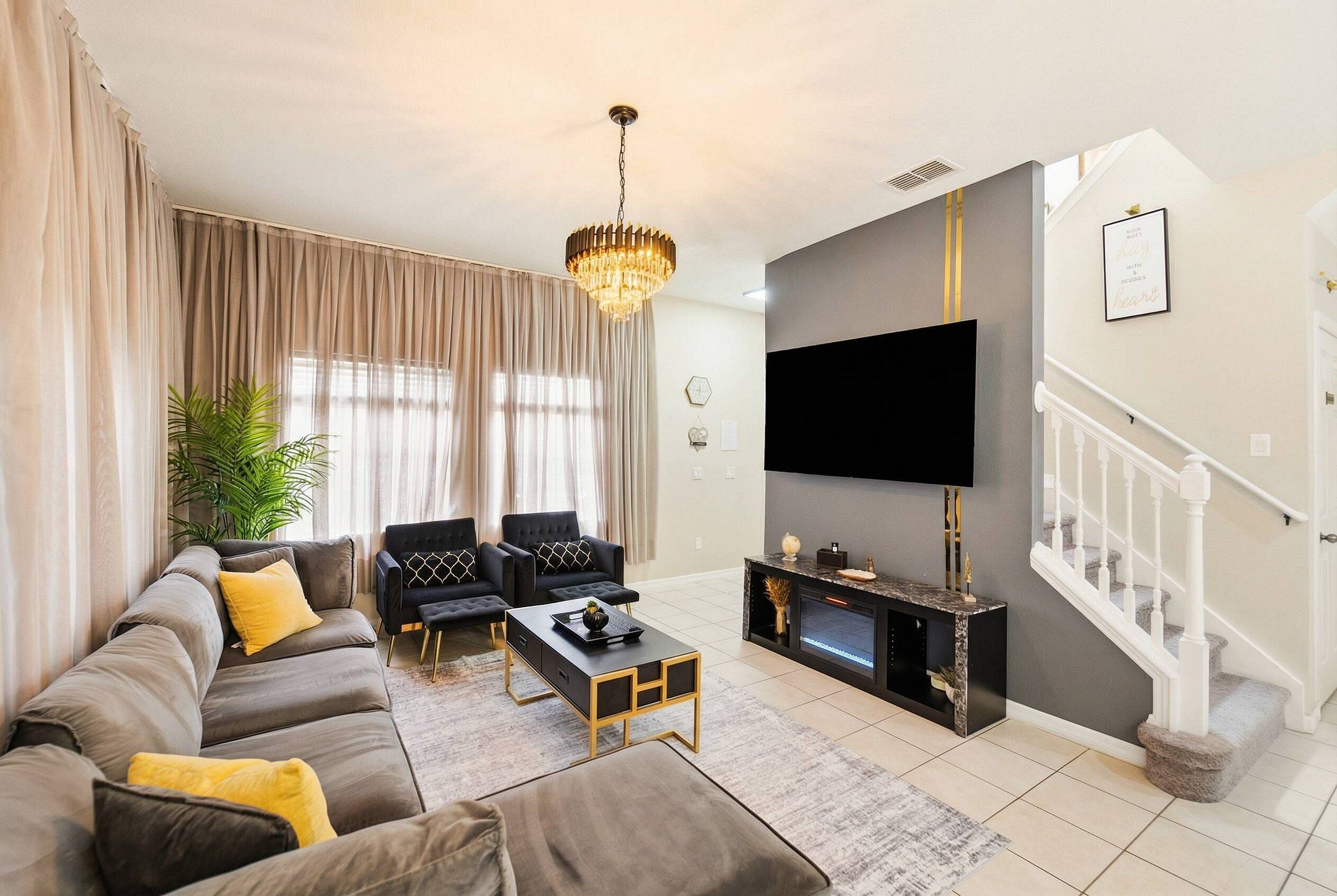 A modern living room with a sofa, chairs, a coffee table, a TV, and a fireplace.