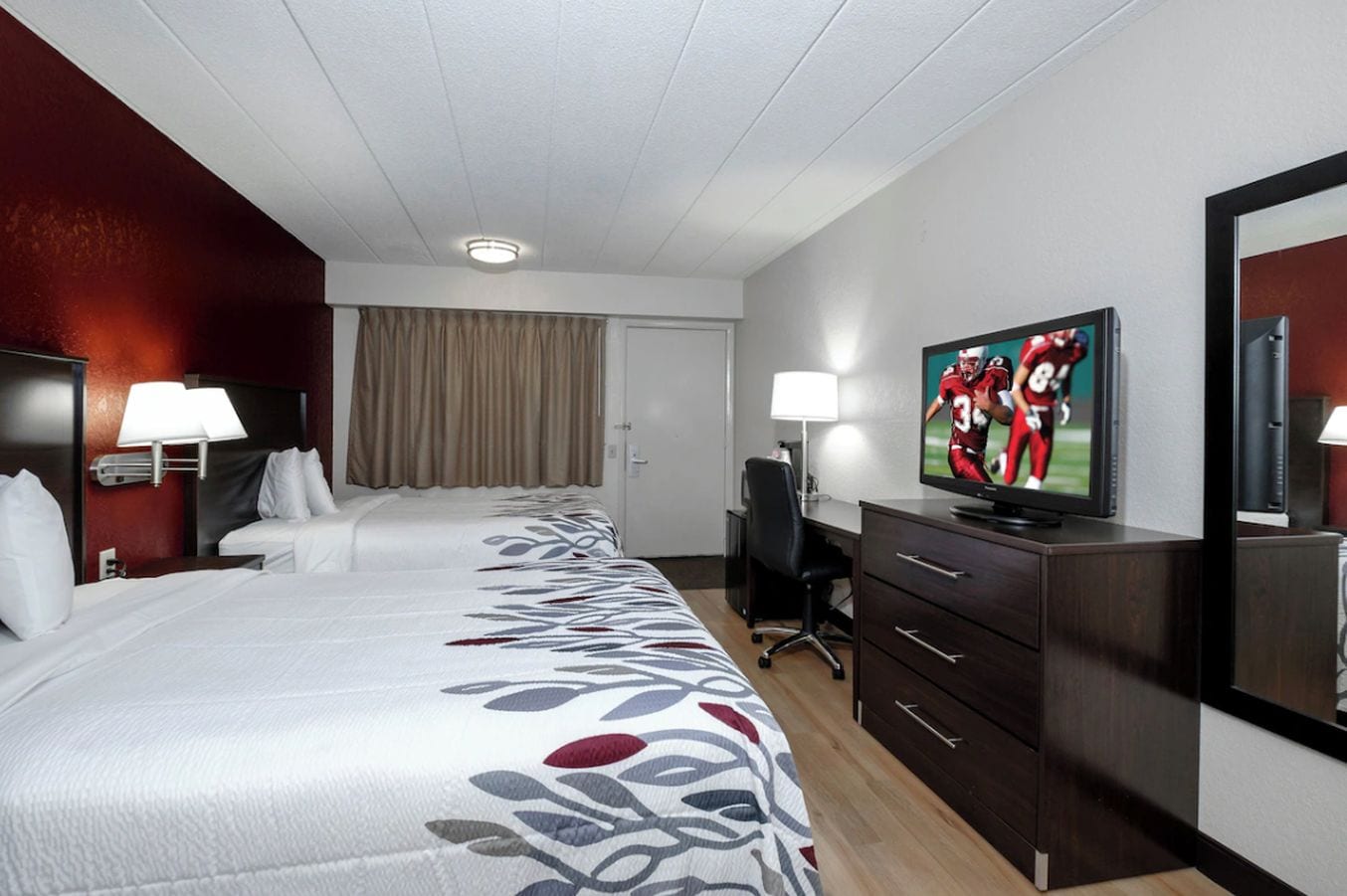 Une chambre d’hôtel avec un grand lit, un bureau, une télévision et une armoire.