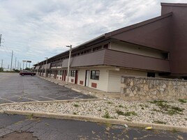 A row of motel buildings with a parking lot in front.