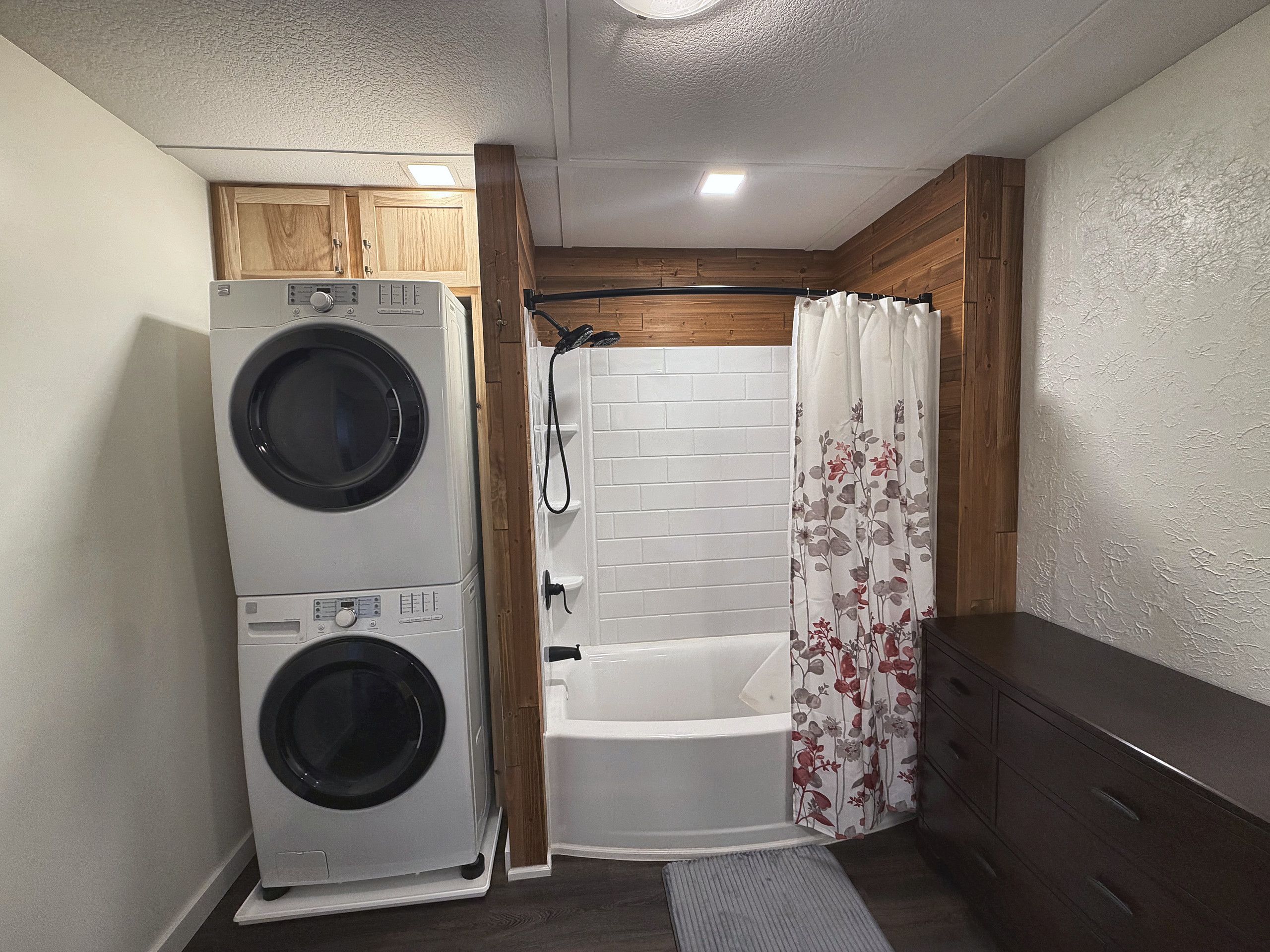 A compact bathroom with a washing machine, a bathtub, and a shower curtain.