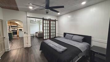 A bedroom with a bed, a nightstand, a ceiling fan, and a sliding door leading to a bathroom.