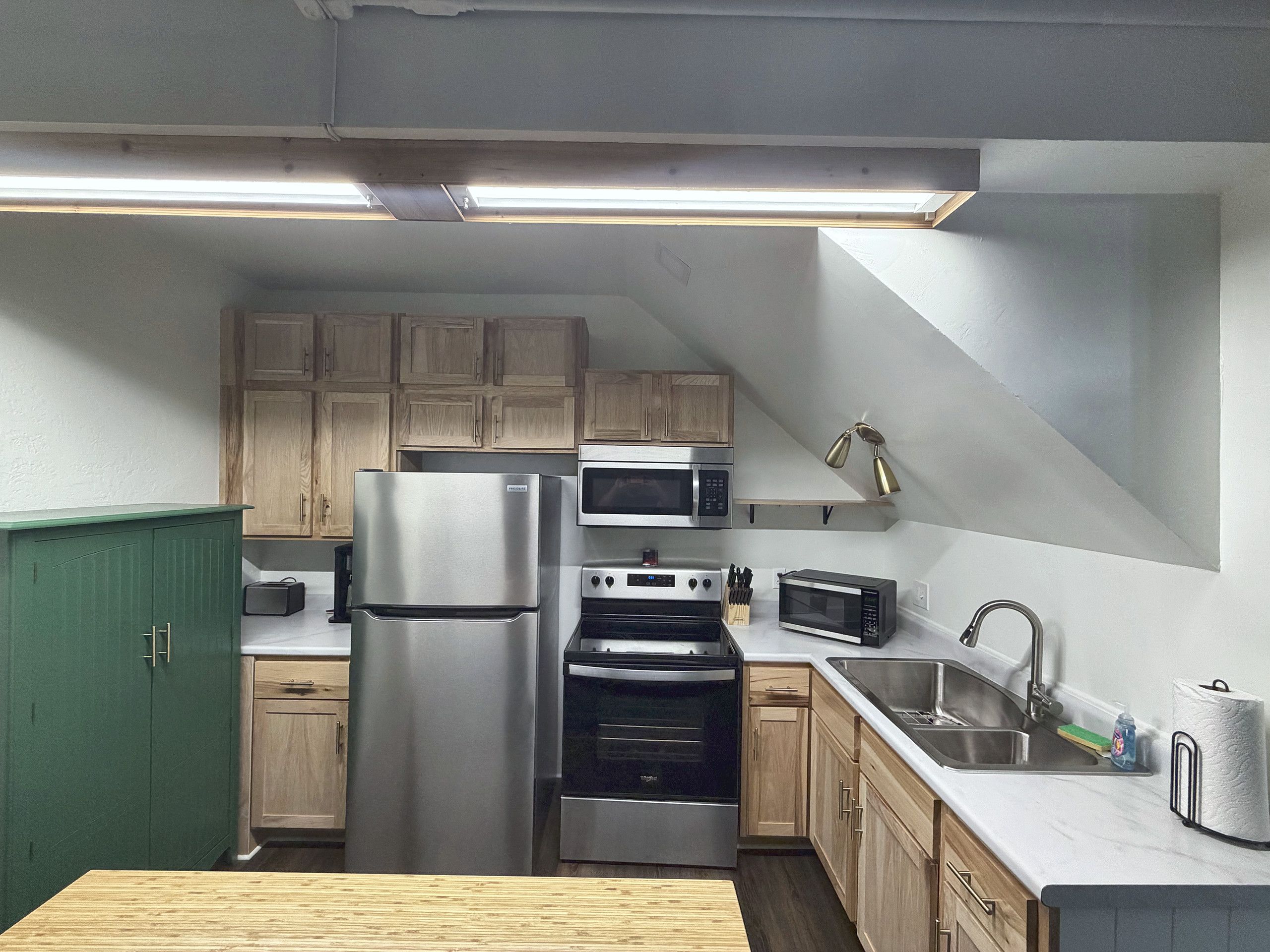 A kitchen with a stainless steel refrigerator, double ovens, a microwave, and wooden cabinets.