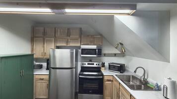 A kitchen with a stainless steel refrigerator, double ovens, a microwave, and wooden cabinets.