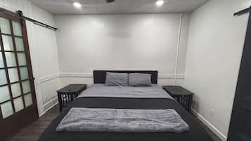 A bedroom with a bed, two bedside tables, a ceiling fan, and a sliding door with frosted glass panels.